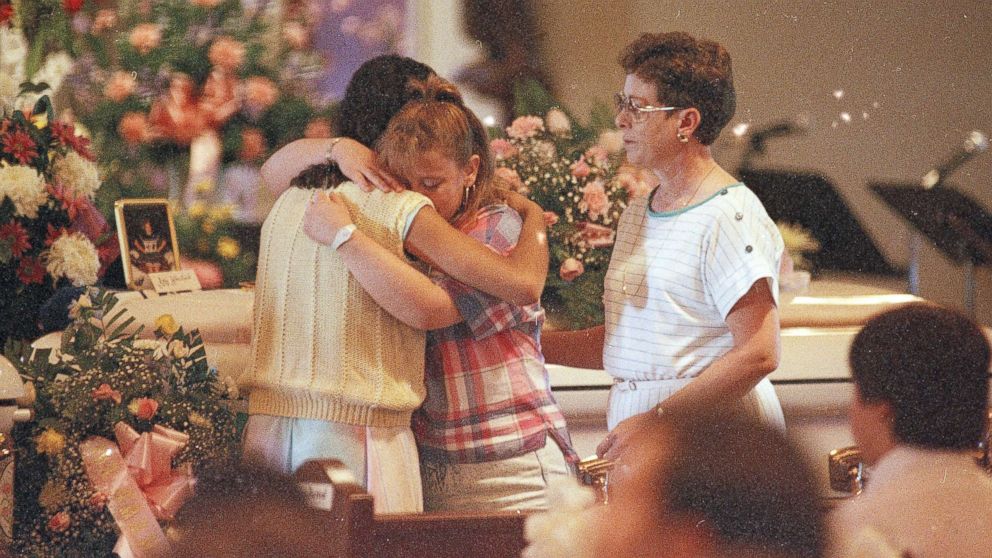 PHOTO: Two young women embrace each other as they stand in front of the casket of Amy Christine Wheelock during her funeral Mass at St. Christopher Church in Radcliff, Ky., May 18, 1988.