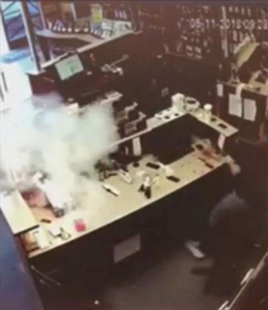 PHOTO: A frame taken from a video showing an iPhone that burst into flames, at left, just a few feet away from an employee at a store. 