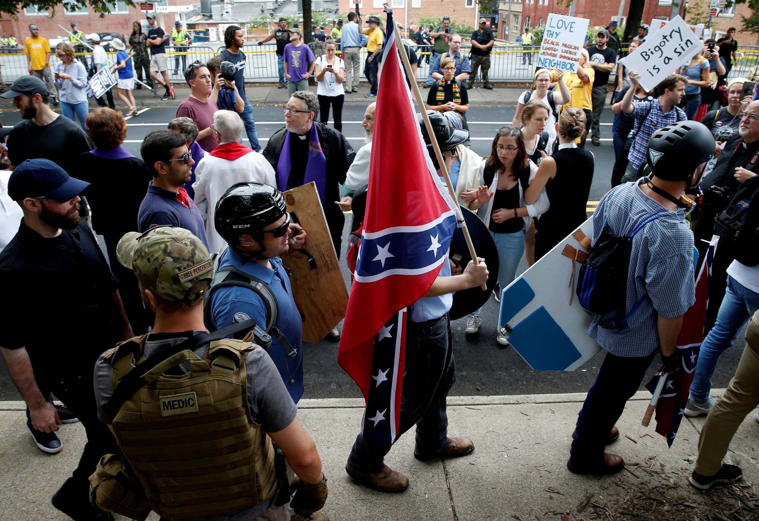 PHOTO: A white supremacist carries the Confederate flag as he walks past counter demonstrators in Charlottesville, Va., Aug. 12, 2017. 