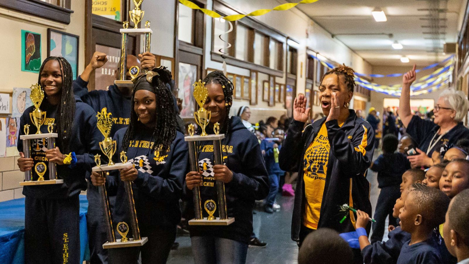 PHOTO: Imani Wilson, Trechelle Williams, and Shakira Luster walk the halls with their trophies of St. Ethelreda during their school's pep rally.