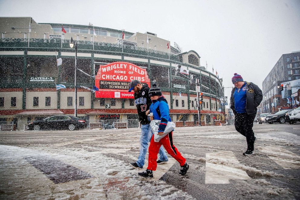 PHOTO: Pedestrians walk through the snow near Wrigley Field after the Cubs game was canceled due to weather Sunday April 14, 2019, in Chicago.