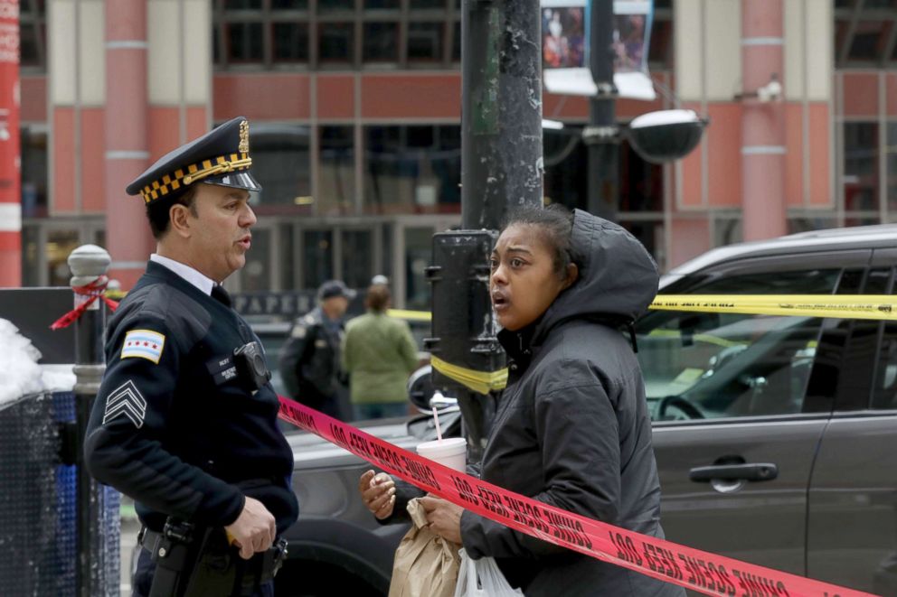 PHOTO: A Chicago Police officer speaks a with a pedestrian at the scene where an off-duty officer was shot while assisting a tactical team at a state government office building, Feb. 13, 2018, in Chicago.