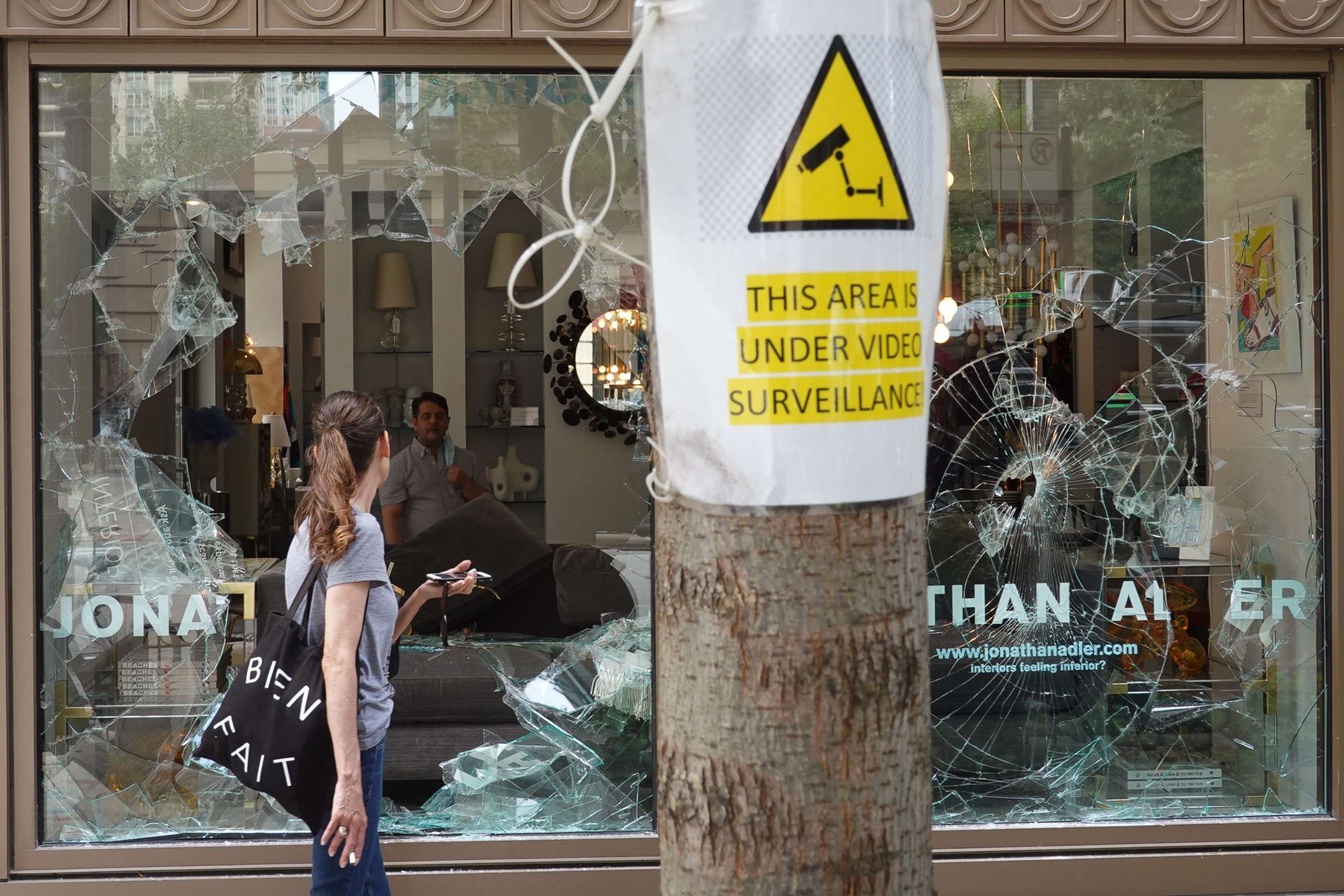 PHOTO: A woman looks through the shattered glass window of an interior design store that was looted on Aug. 10, 2020, in Chicago.