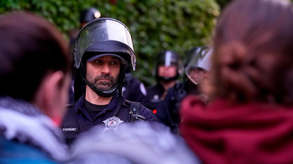 PHOTO: A police officer stands guard blocking pro-Palestinian protesters from returning to their encampment as the encampment is dismantled at the University of Chicago, Tuesday, May 7, 2024. 