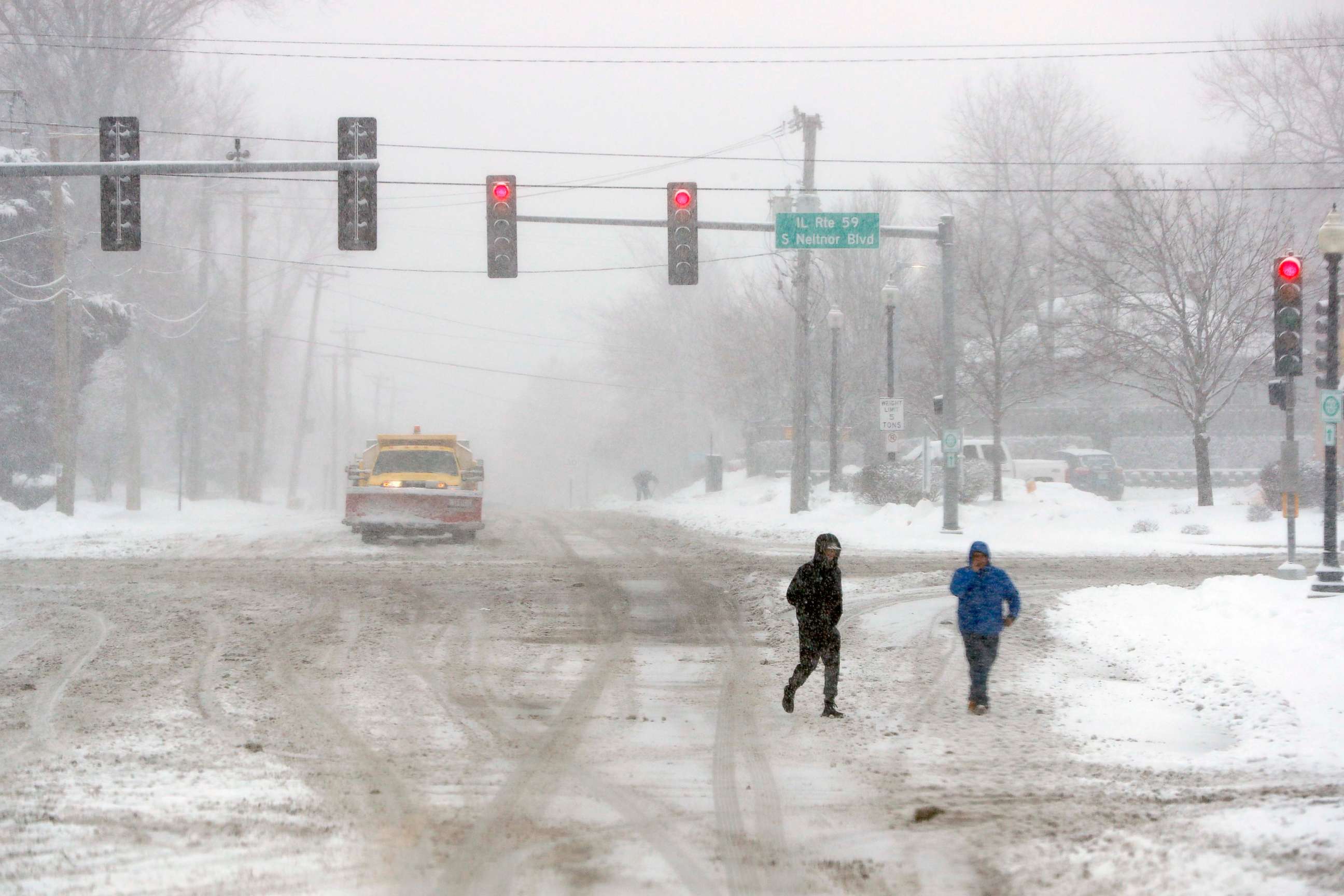 PHOTO: Two unidentified men cross the street after heavy snow fall on Jan. 26, 2021, in West Chicago, U.S.