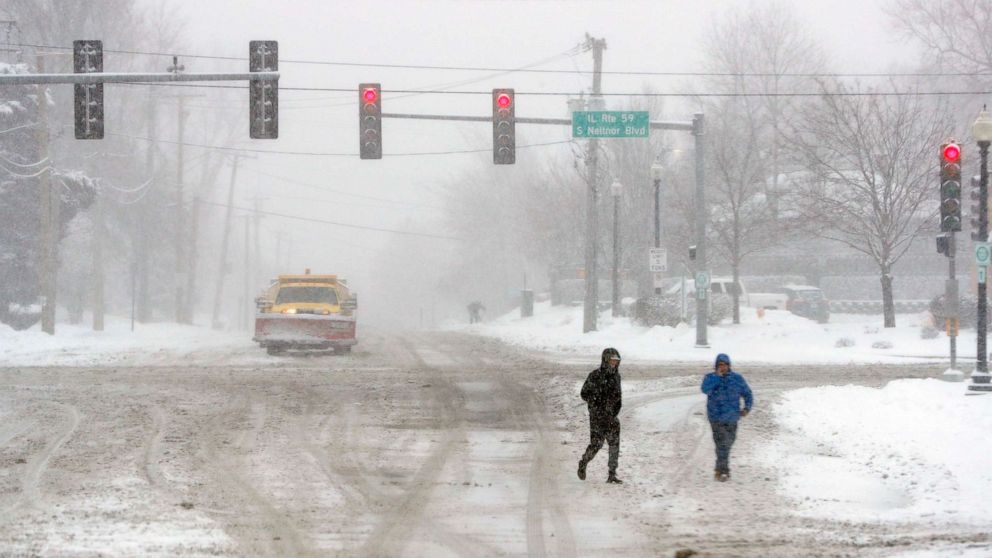 PHOTO: Two unidentified men cross the street after heavy snow fall on Jan. 26, 2021, in West Chicago, U.S.