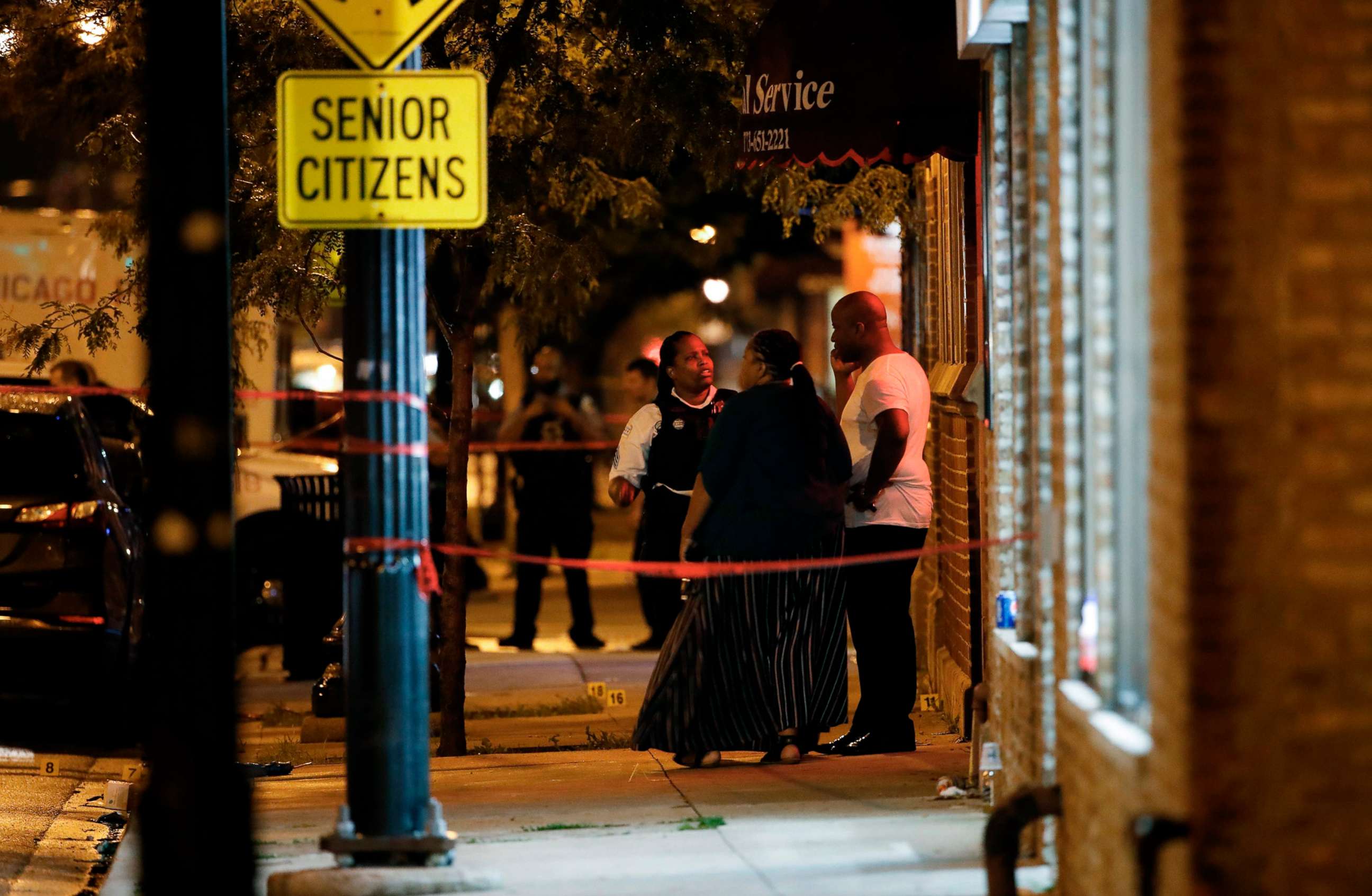 PHOTO: A Chicago police officer talks with people in front of Rhodes Funeral Services as evidence markers are seen on the ground at the scene of a shooting in Chicago, July 21, 2020.