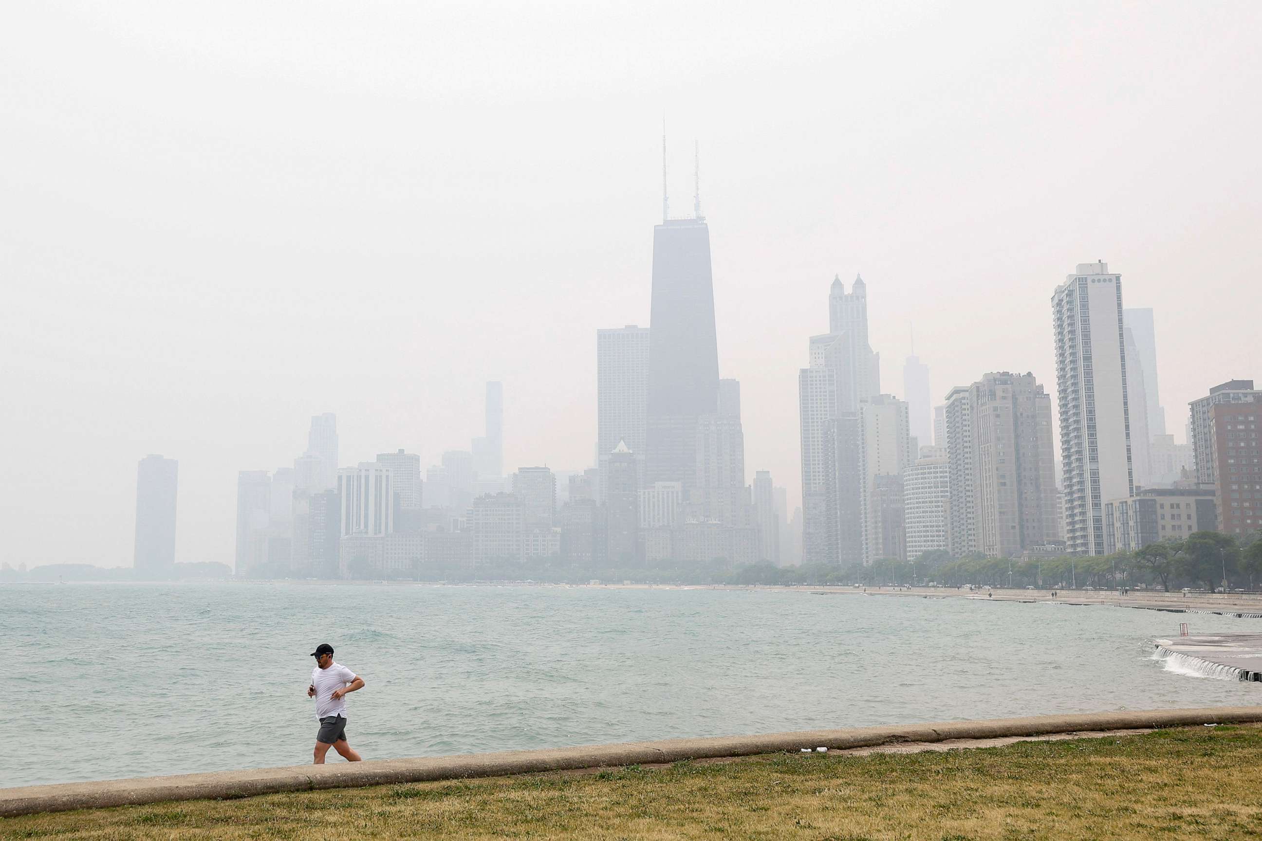 PHOTO: A jogger runs along the shoreline of Lake Michigan with heavy smoke from the Canadian wildfires, June 27, 2023, in Chicago, Illinois.