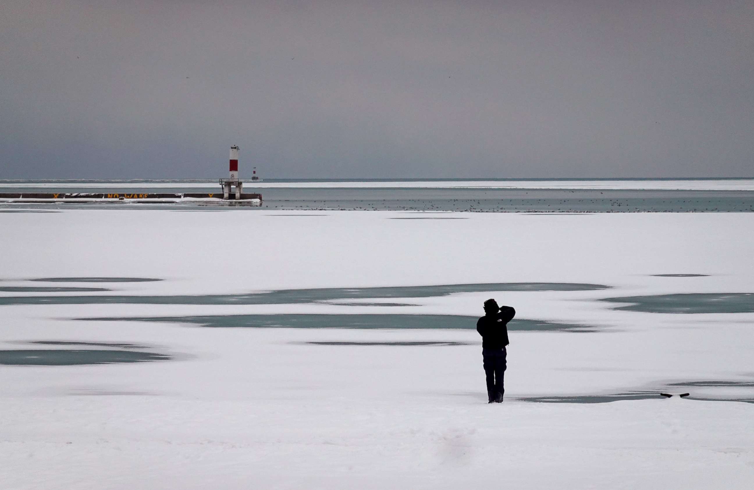 PHOTO: A man takes a picture along the  frozen shoreline of Lake Michigan on Ja. 24, 2022 in Chicago.