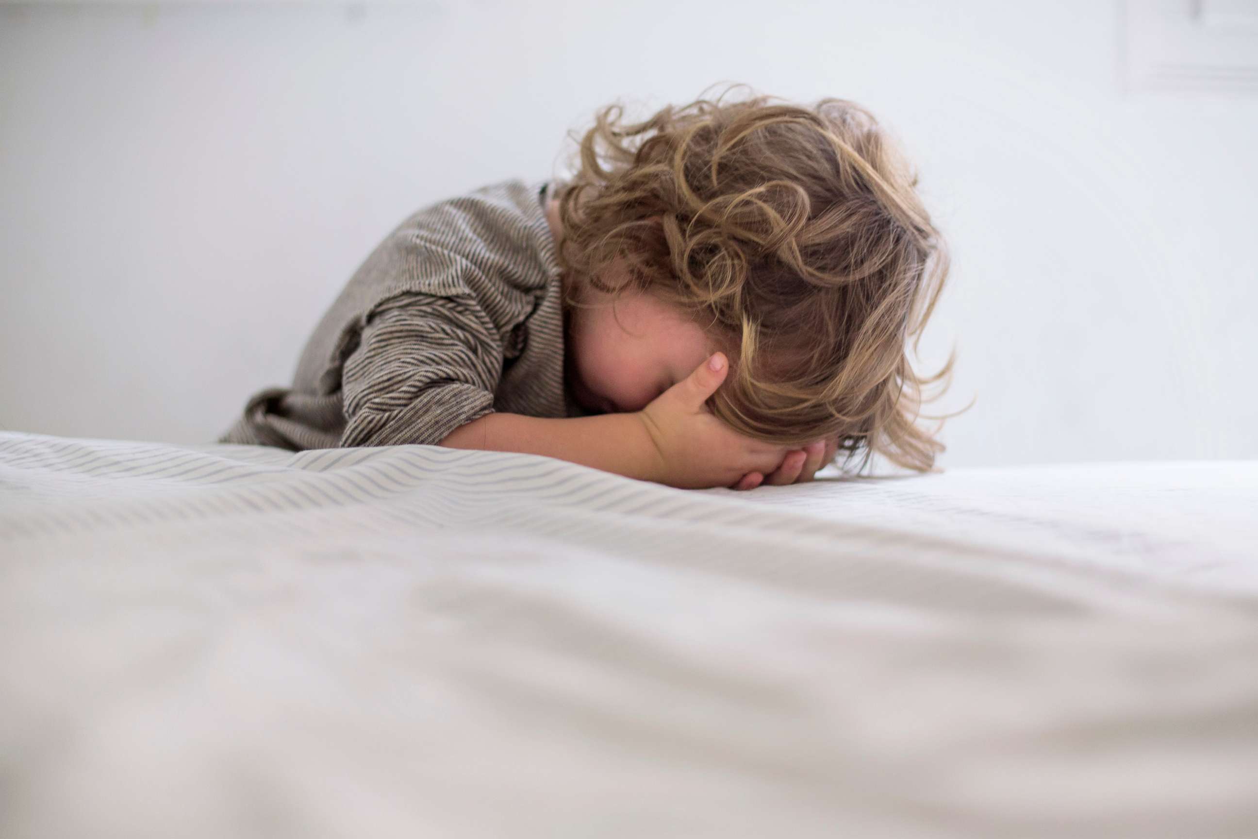 PHOTO: A child hides his face, child abuse. sad child stock photo. 