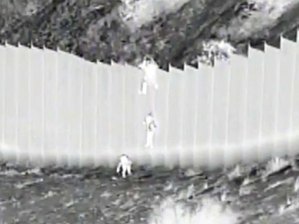 PHOTO: This photo taken from night video and provided by the United States Customs and Border Protection shows a smuggler dropping children from the top of a border barrier near Santa Teresa, New Mexico, on March 30, 2021.