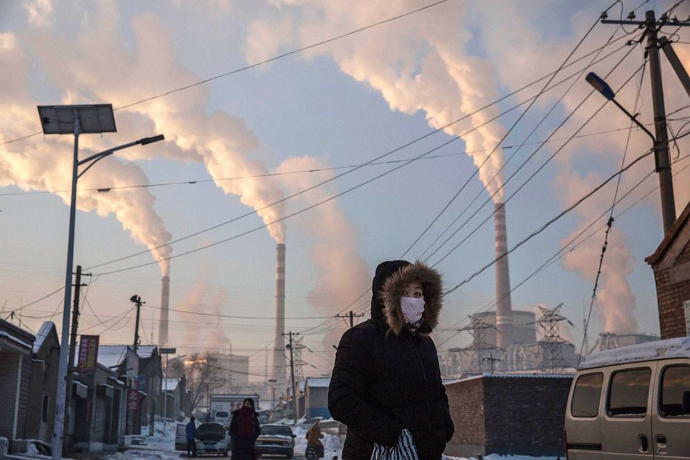 PHOTO: A woman wears a mask while walking in a neighborhood next to a coal fired power plant on Nov. 26, 2015, in Shanxi, China.