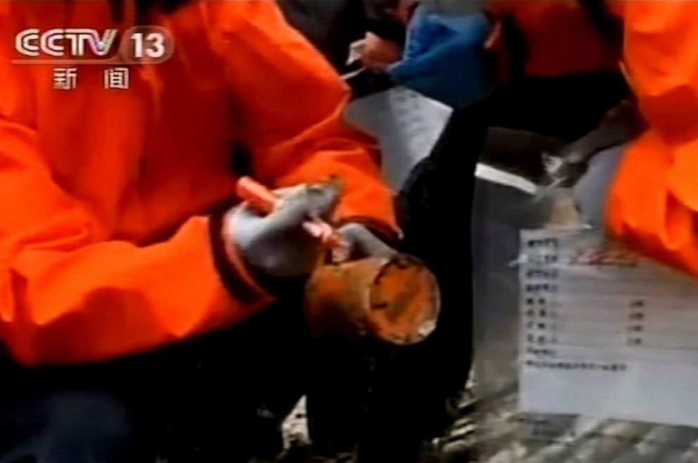 PHOTO: An emergency worker holding an orange-colored 'black box' recorder found at the China Eastern flight crash site, March 23, 2022, in Tengxian County in southern China's Guangxi Zhuang Autonomous Region.