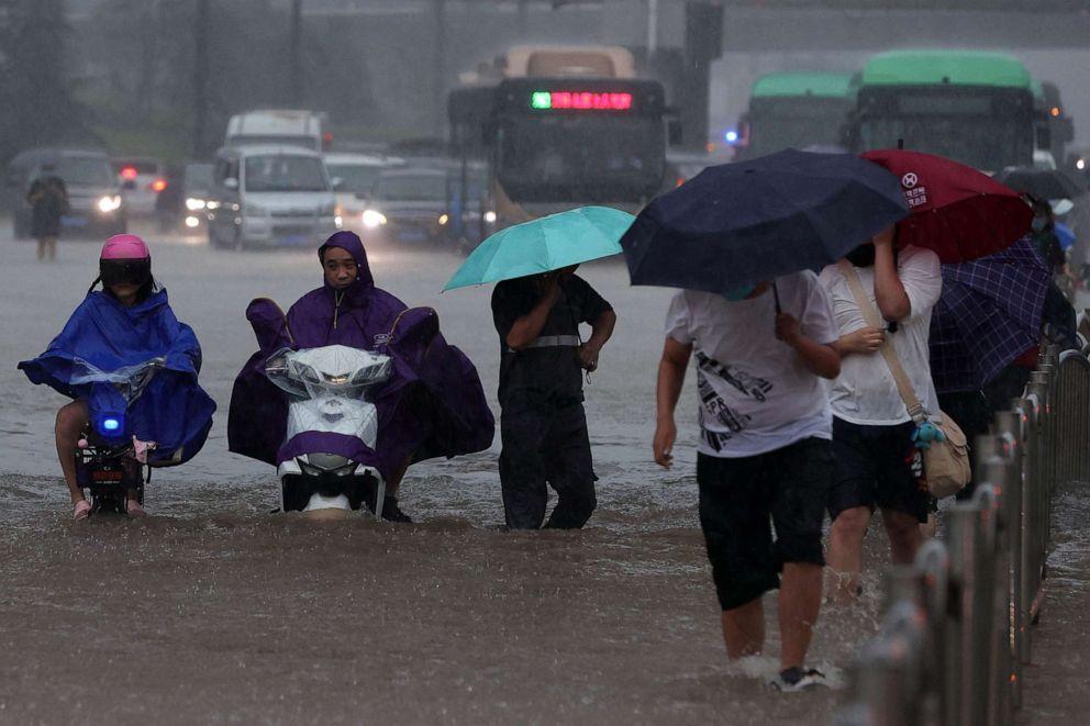 PHOTO: People wade through flood waters along a street during heavy rain in Zhengzhou in China's central Henan province, July 20, 2021.