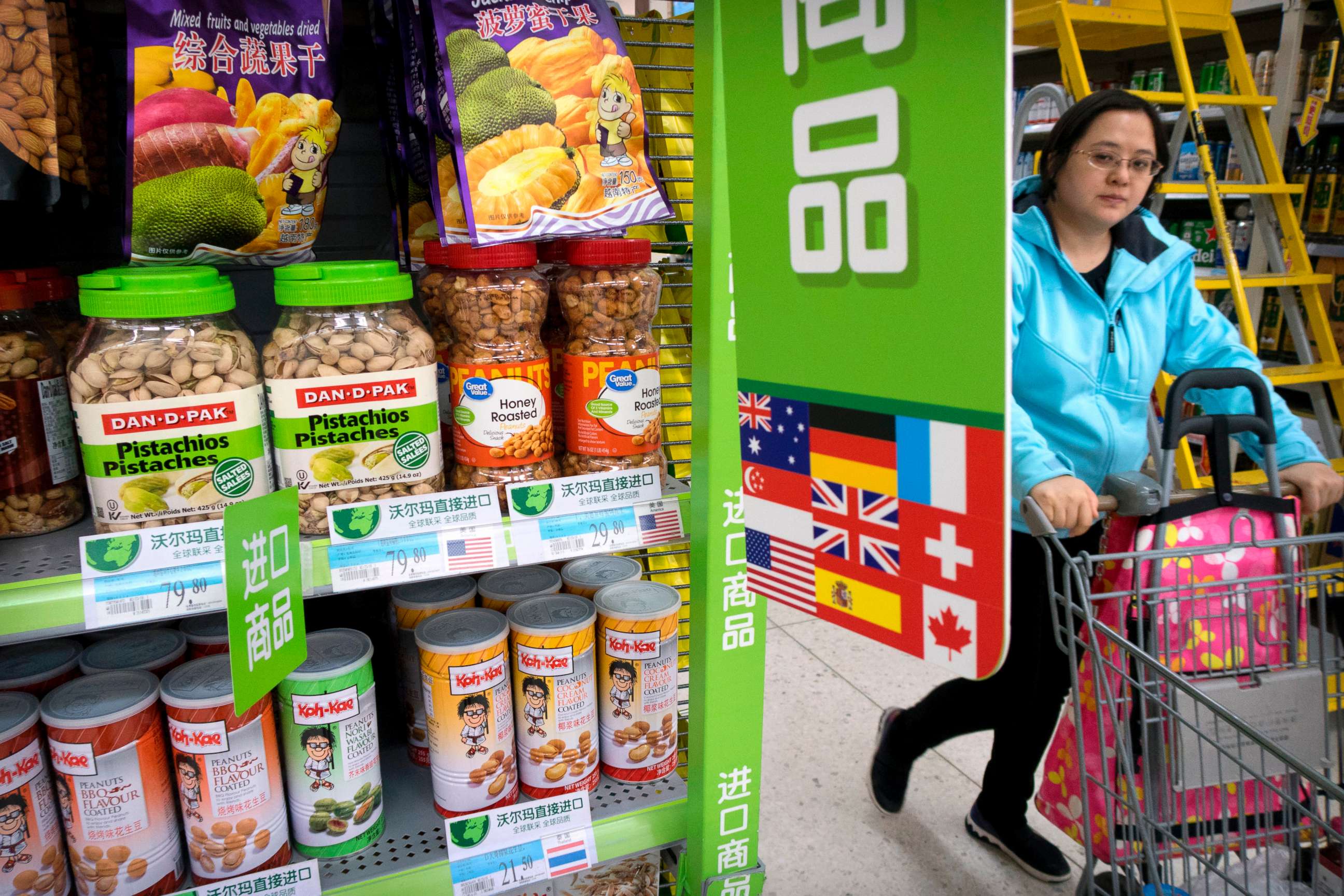 PHOTO: A woman pushes a shopping cart past a display of nuts imported from the United States at a supermarket in Beijing, March 23, 2018. 