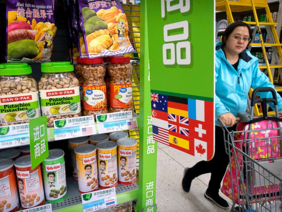 PHOTO: A woman pushes a shopping cart past a display of nuts imported from the United States at a supermarket in Beijing, March 23, 2018.