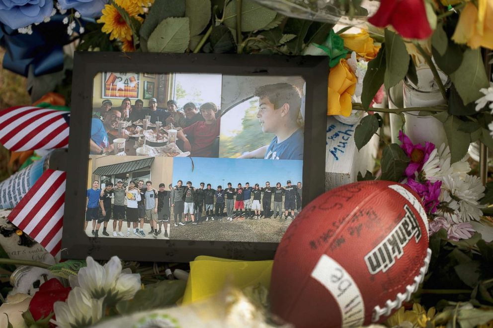 PHOTO: Photos, a football and flowers sit in front of a cross bearing the name of Chris Stone at a memorial in front of Santa Fe High School, May 22, 2018 in Santa Fe, Texas.