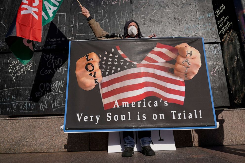 A protester holds a sign across the street from the Hennepin County Government Center, April 6, 2021,in Minneapolis where testimony continues in the trial of former Minneapolis police officer Derek Chauvin charged with murder in the death of George Floyd.