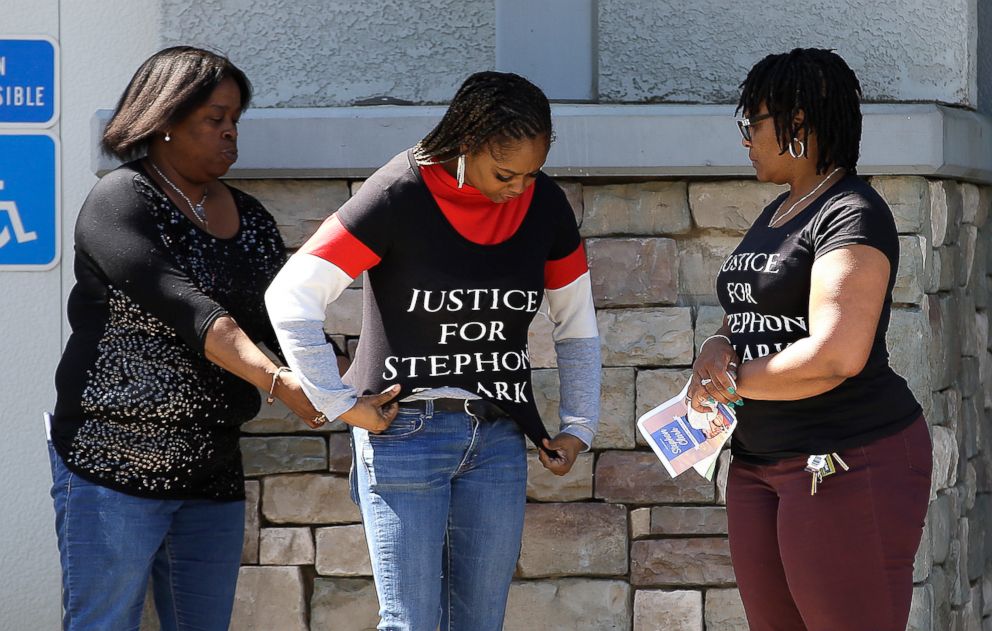 PHOTO: A woman gets help putting on a T-shirt calling for Justice For Stephon Clark, before entering the Bayside of South Sacramento Church for Clarks' wake, March 28, 2018, in Sacramento, Calif. 