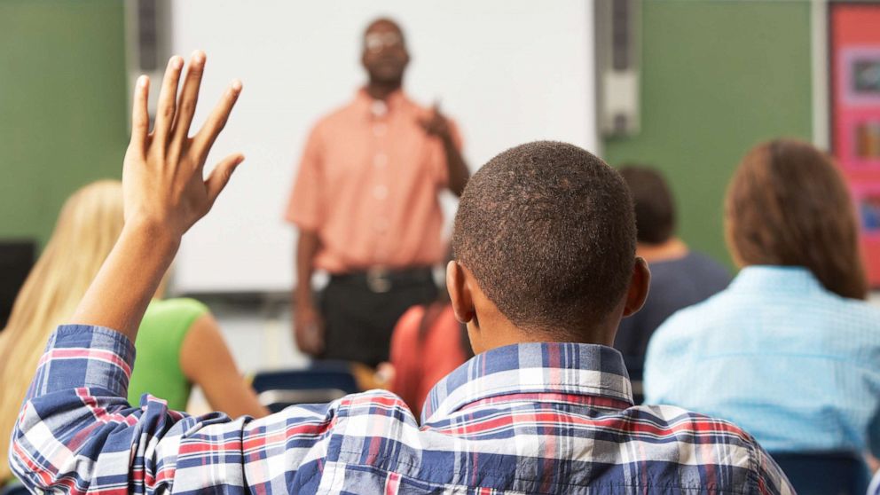 PHOTO: A student raises his hand in a classroom.