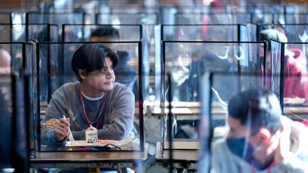 PHOTO: Students sit separated by plastic dividers during lunch at Wyandotte County High School in Kansas City, Kan. on the first day of in-person learning, March 31, 2021. 