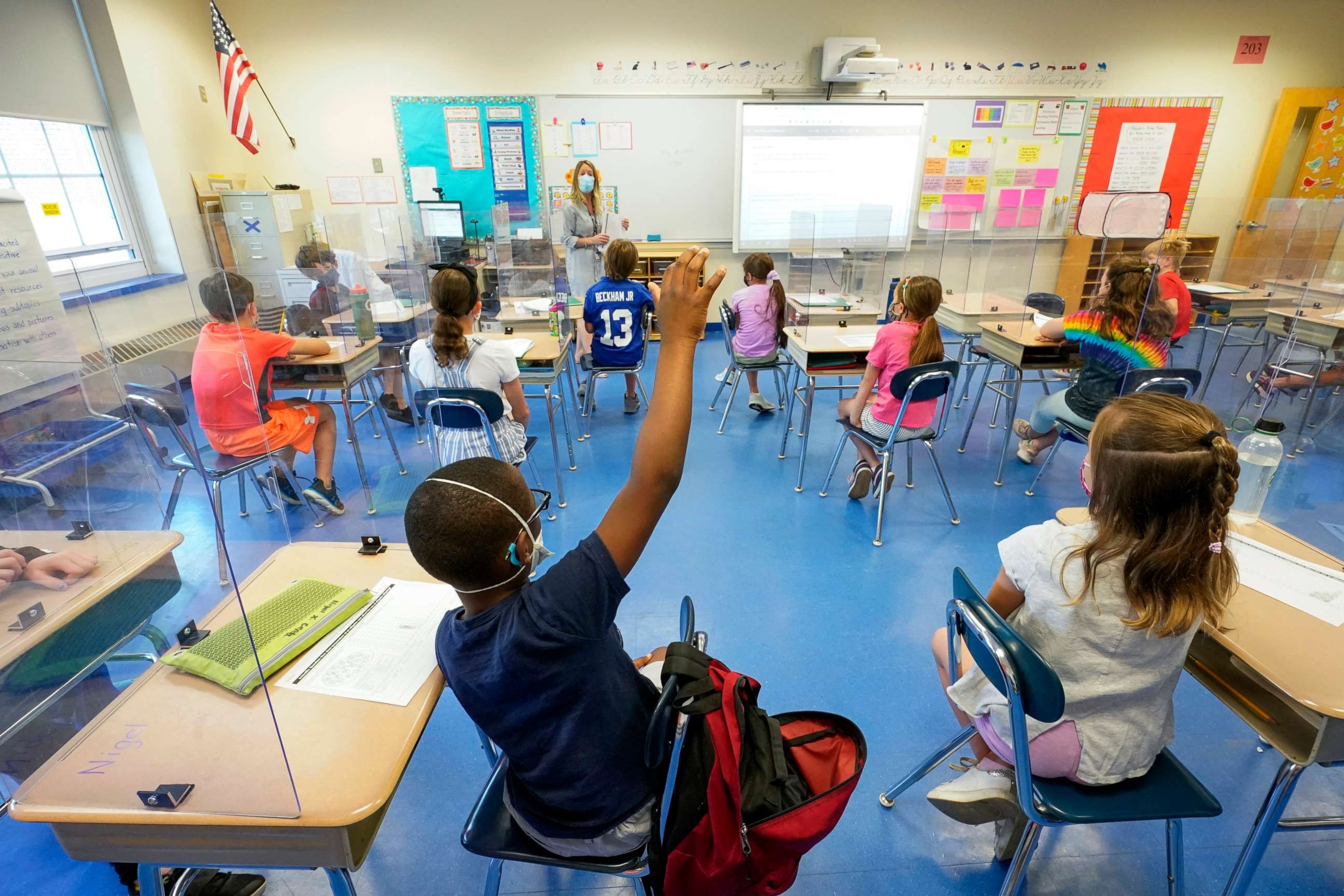 PHOTO: A teacher, center, and her third grade students wear face masks and are seated at proper social distancing spacing during as she conducts her class in Rye, N.Y., May 18, 2021.