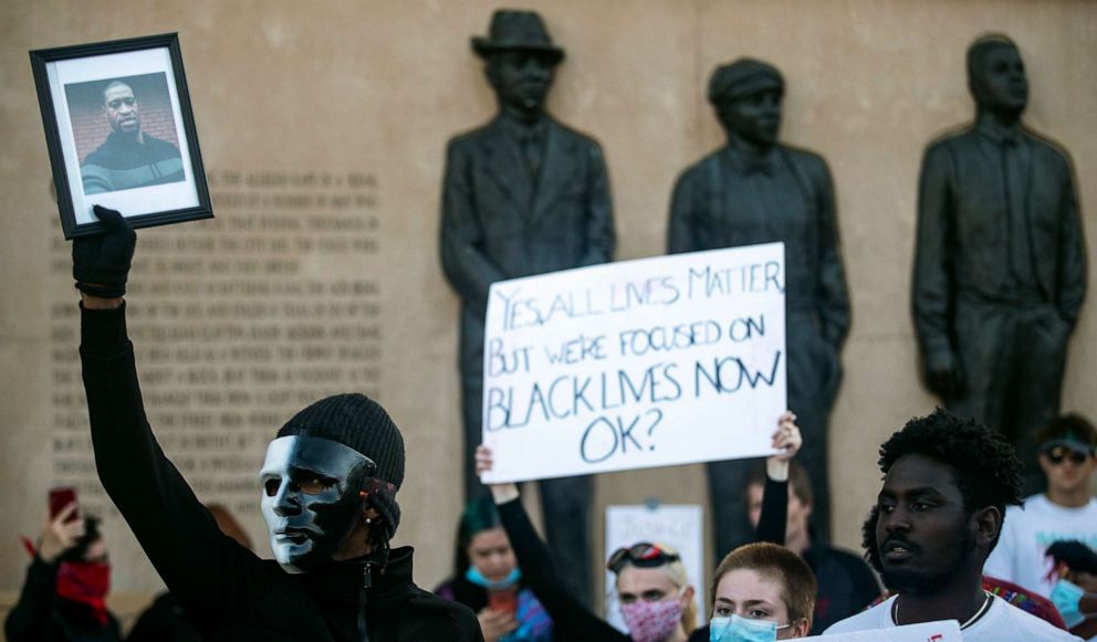 PHOTO: In this May 30, 2020 photo, a protestor holds up a photo of George Floyd in front of the Clayton, Jackson, McGhie Memorial as part of a large protest in Duluth, Minn.
