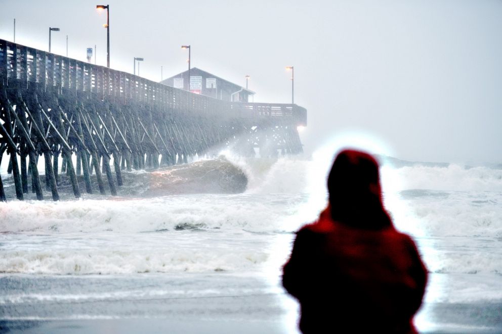 PHOTO:  A person watches waves crashing against the Pier at Garden City, S.C., Aug. 3, 2020.