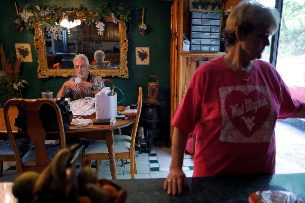 PHOTO: Retired coal miner Kennith Adams, who has complicated black lung disease and lives connected to an oxygen supply 24-hours a day, inhales medicine while his wife Tammie keeps him company, at their home in Princeton, W.Va., May 17, 2018.