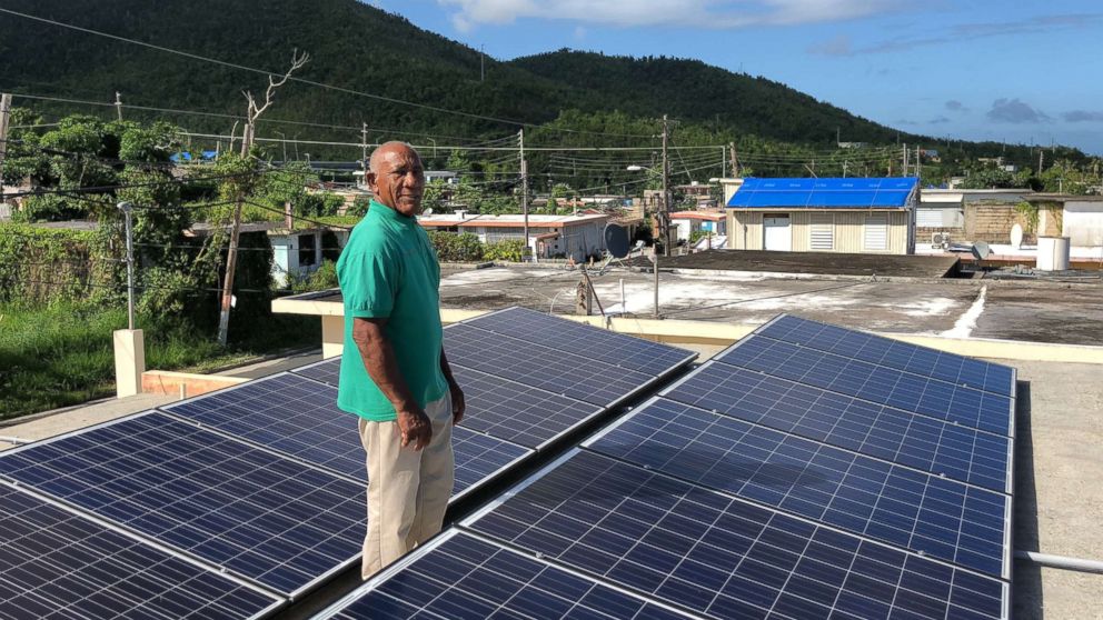 Community leader Angel Colon with the solar panels atop a building in Daguao, Puerto Rico.