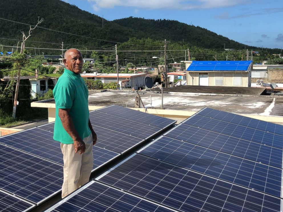 Community leader Angel Colon with the solar panels atop a building in Daguao, Puerto Rico.