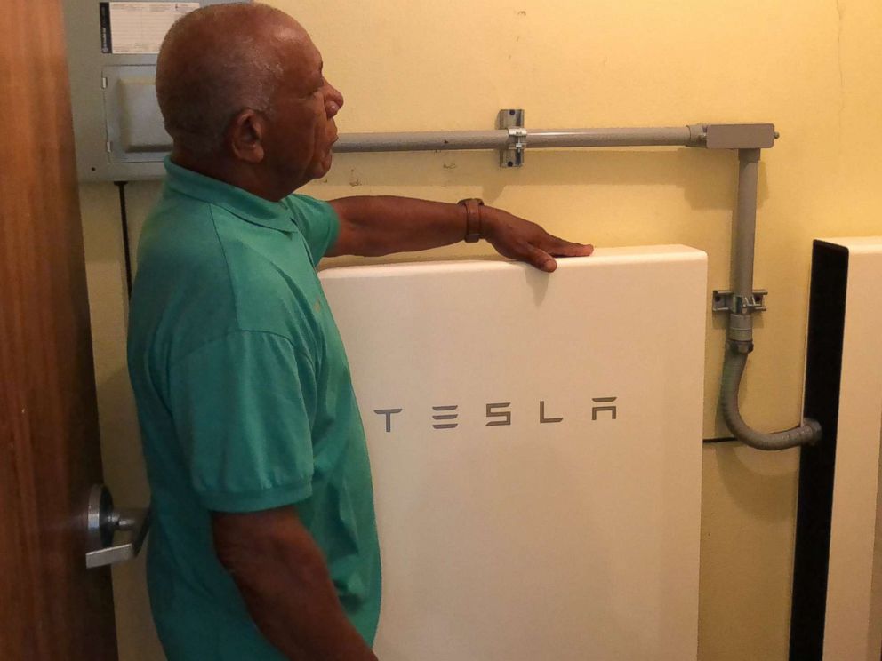 Community leader Angel Colon next to a TESLA Powerwall battery, which stores solar energy.