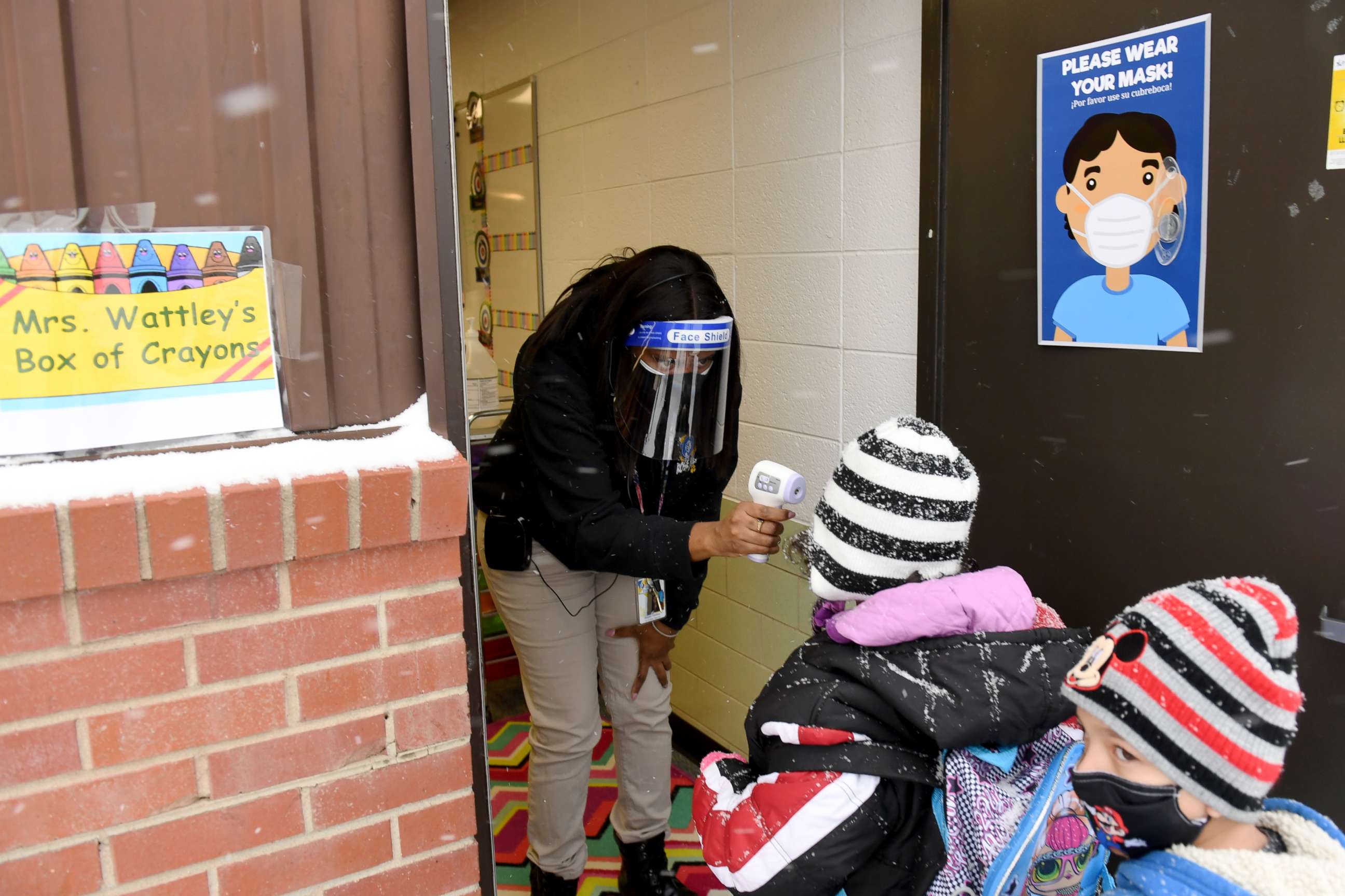 PHOTO: Teacher Raven Wattley checks body temperature of students by the entrance of the class room at Rose Hill Elementary school in Commerce City, Colorado, Jan. 26, 2021.