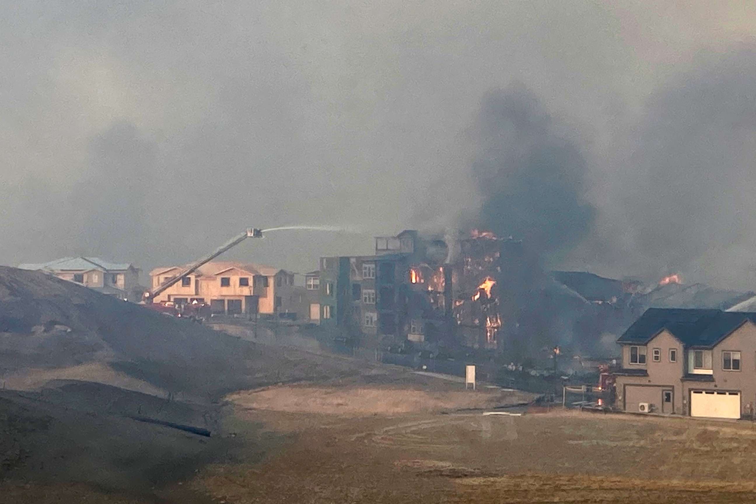 PHOTO: Firefighters spray water on a structure fire as a wildfire burns, Thursday, Dec. 30, 2021, in Superior, Colo. Thousands of residents in Superior and Louisville, two communities near Denver, were ordered to evacuate Thursday.