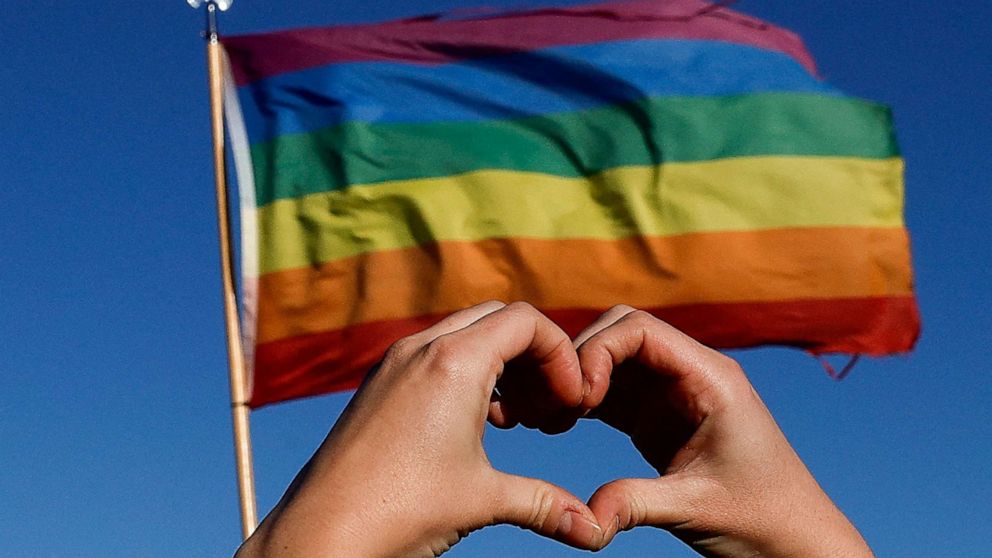 PHOTO: A person holds their hands in the shape of a heart in front of a pride flag during a march for solidarity for the those affected after a mass shooting at LGBTQ nightclub Club Q, in Colorado Springs, Colorado, Nov. 26, 2022.