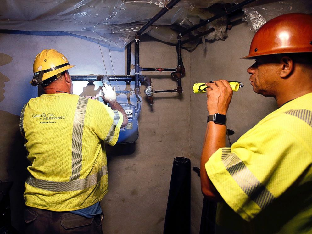 PHOTO: Columbia Gas employee Brian Jones shines a flashlight so his partner, using a wrench, can shut off the gas in a home Friday, Sept. 14, 2018, in Andover, Mass.
