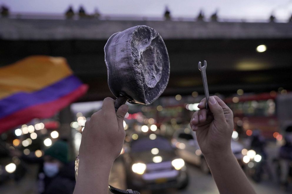 PHOTO: A demonstrator bangs a pot among traffic on the north highway of the city during the sixth day of the national strike, May 4, 2021, in Bogota, Colombia.