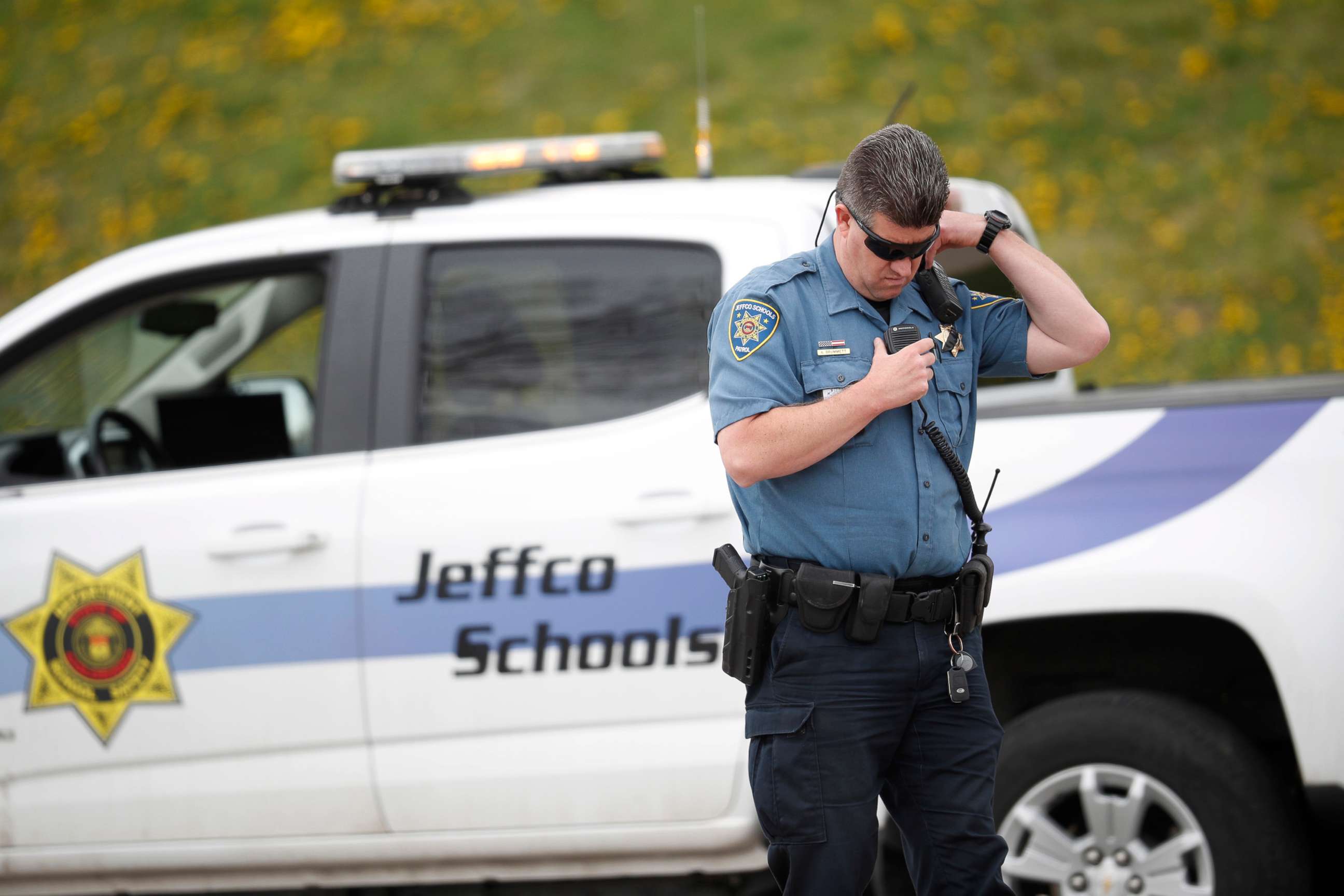 PHOTO: An officer from Jefferson County, Colo., Schools listens on his radio as students leave Columbine High School, April 16, 2019, in Littleton, Colo.
