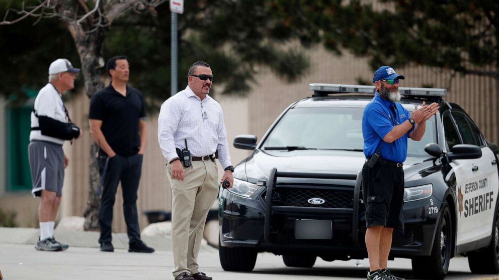School police officers look on as students leave Columbine High School, April 16, 2019, in Littleton, Colo.