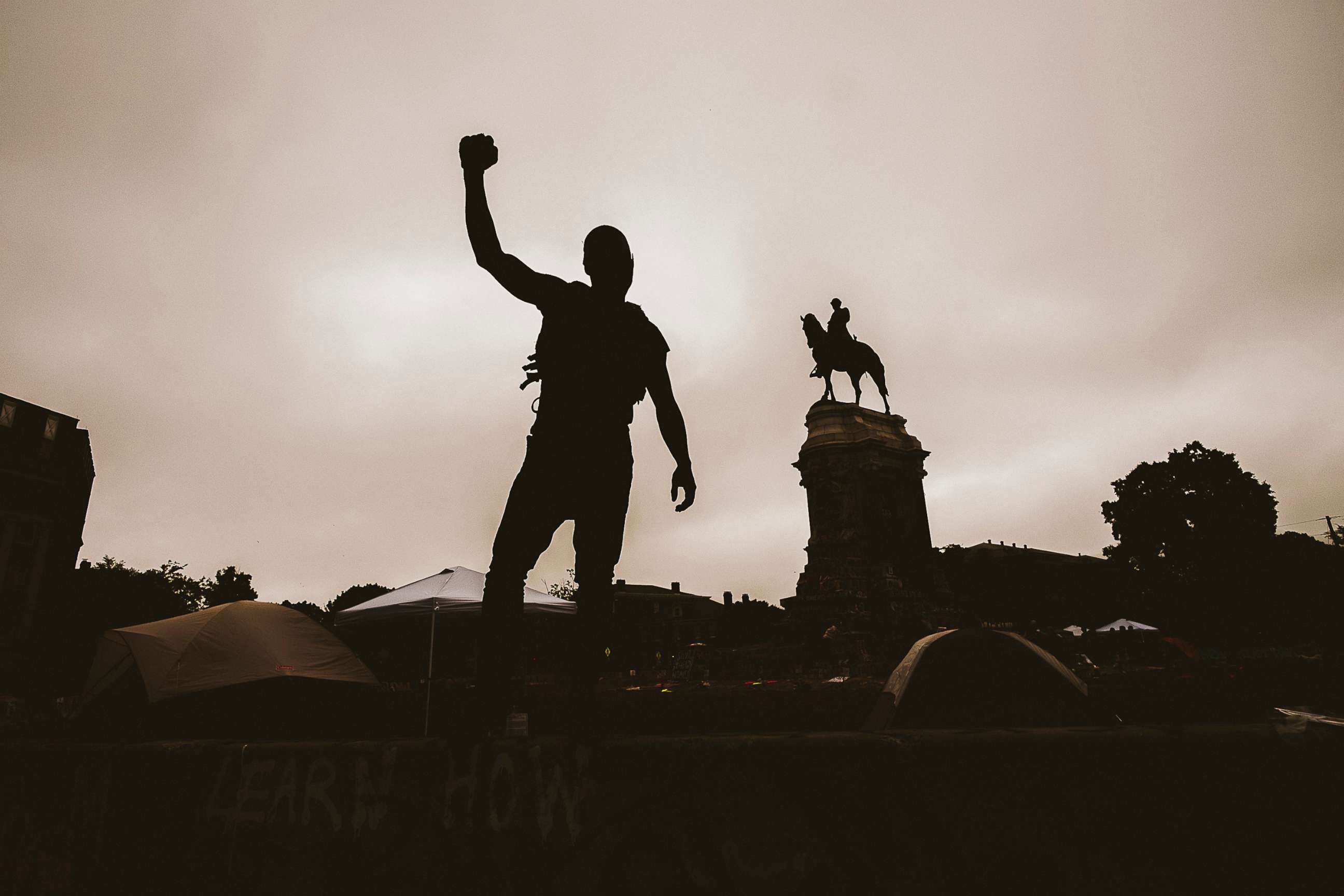 PHOTO: A protester raises their fist in the air at the Robert E. Lee monument in Richamond, Va., June 20, 2020.