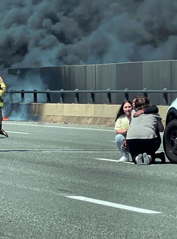 PHOTO: This photo provided by Angelique Feliciano shows people embracing as firefighters and police respond after a crash involving a fuel truck and a car sparked a fire on the Gold Star Bridge between New London and Groton, Conn., on April 21, 2023.