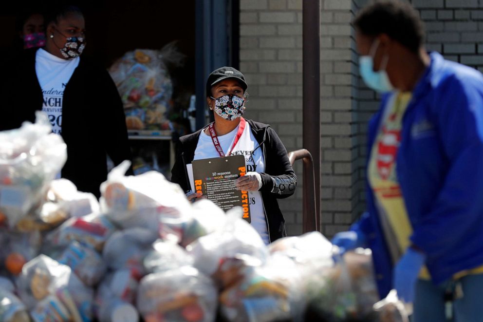 PHOTO: T.W. Browne Middle School food service employee Portia Lacy, center, uses a clipboard with paperwork to keep track of the amount of bags of food being distributed at the school in Dallas, Thursday, April 16, 2020.