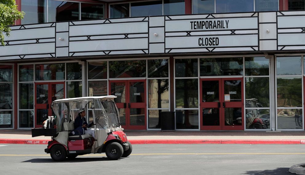 PHOTO: A worker passes a theater that has been closed due to the coronavirus outbreak, in San Antonio, Thursday, April 16, 2020. San Antonio remains under stay-at-home orders due to the COVID-19 outbreak.