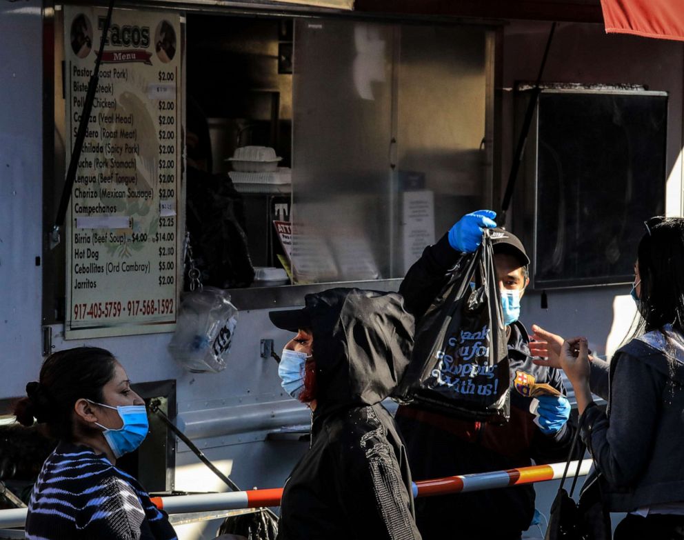 PHOTO: People wear masks to help stop the spread of the new coronavirus while while buying food from a food truck on 5th Avenue in Sunset Park, May 5, 2020, in New York.