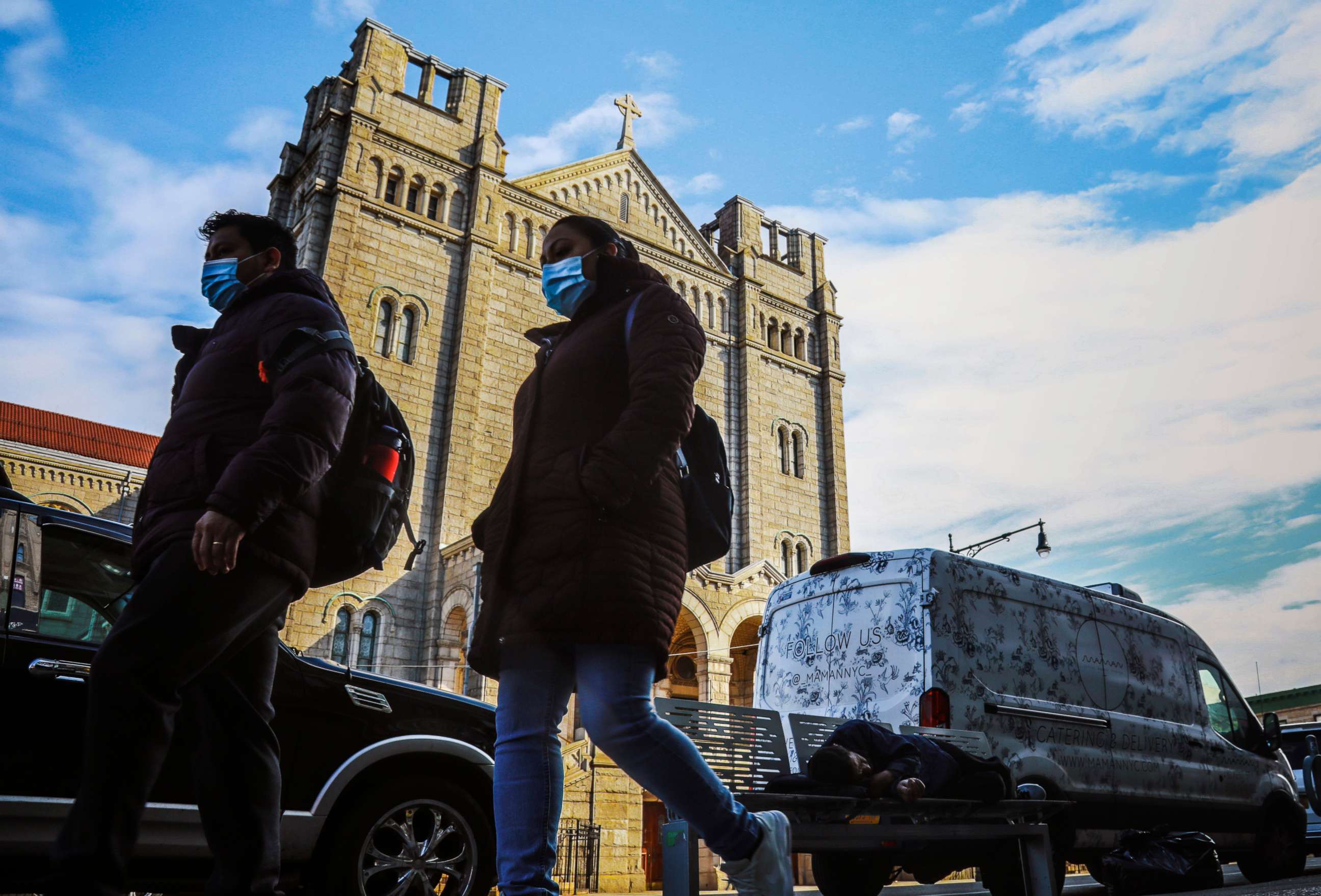 PHOTO: People wearing masks to help stop the spread of the new coronavirus walk past a man sleeping on a bench on 5th Avenue in a Brooklyn neighborhood with one of the city's largest Mexican and Hispanic communities, May 5, 2020, in New York.