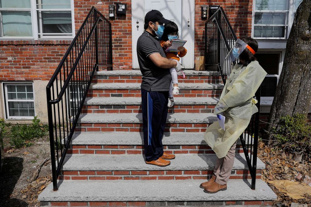 PHOTO: Syed Kamal holds his two year-old daughter Areeba outside their home and talks to Boston Medical Center pediatrician Dr. Sara Stulac in Boston, May 8, 2020.