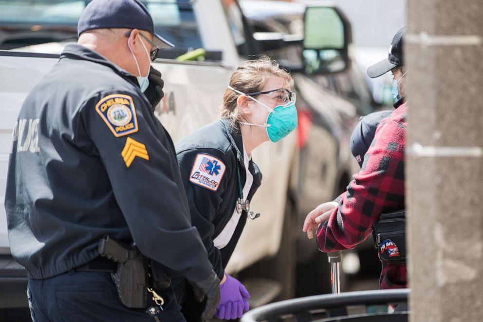 PHOTO: Emergency medical personnel tend to a man who was not feeling well across from Chelsea City Hall on April 17, 2020, in Chelsea, Mass.