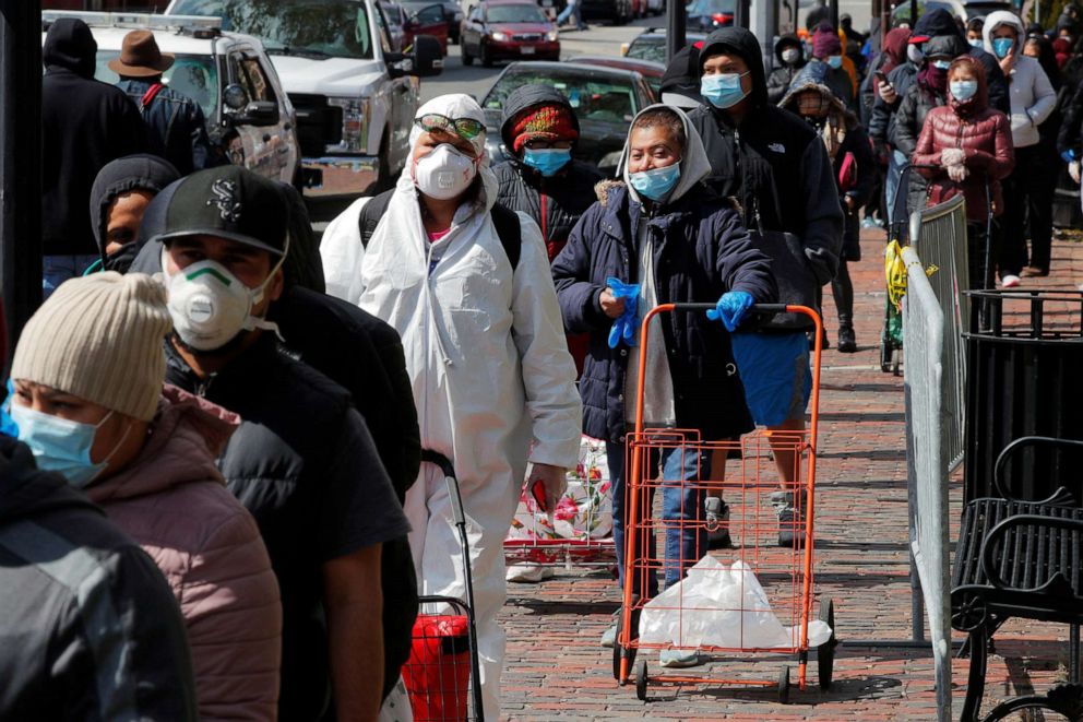 PHOTO: People wearing personal protective equipment wait in a line for a pop-up food pantry amid the coronavirus disease outbreak in Chelsea, Mass., April 17, 2020.