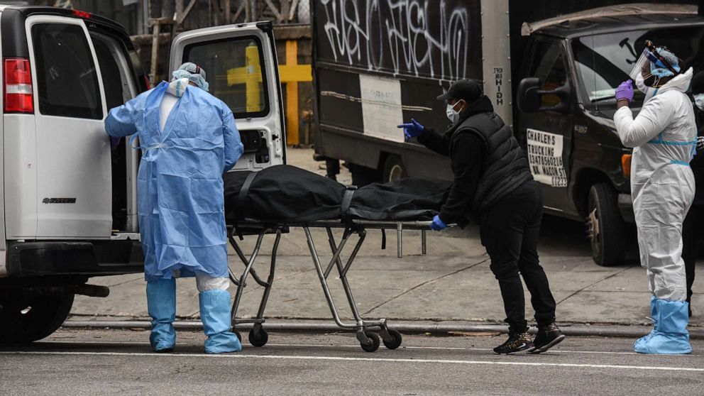 PHOTO: A funeral worker is assisted moving a deceased patient into a van at the Brooklyn Hospital Center, April 27, 2020, in Brooklyn.