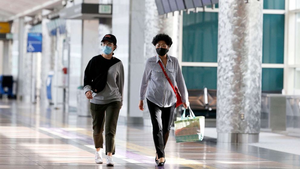 PHOTO: Two travelers wear face masks at Denver International Airport, May 3, 2020, in Denver during the coronavirus pandemic. 